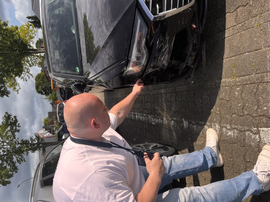 Kfz-Sachverständiger von Schadenzentrum Hamburg begutachtet den Frontschaden eines schwarzen Audi