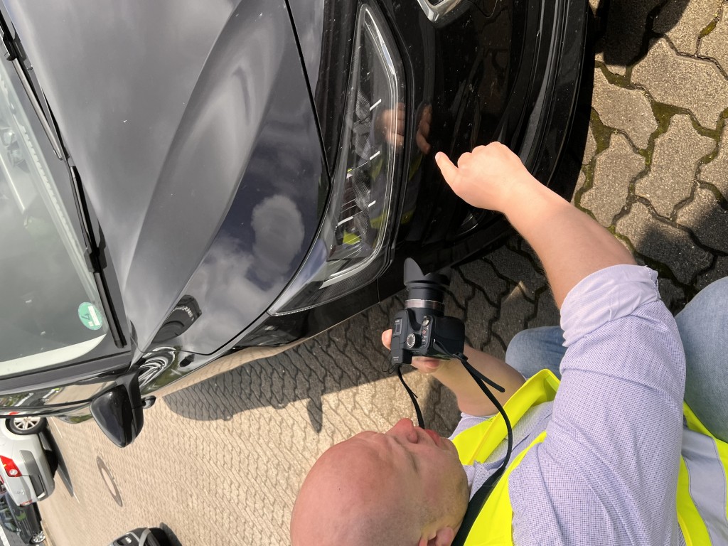 Sachverständiger fotografiert einen Scheinwerfer mit der Kamera
